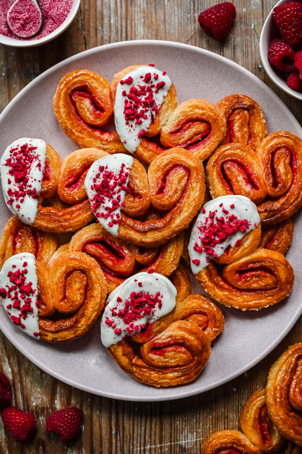 Overhead view of white chocolate dipped raspberry palmiers on a plate. 