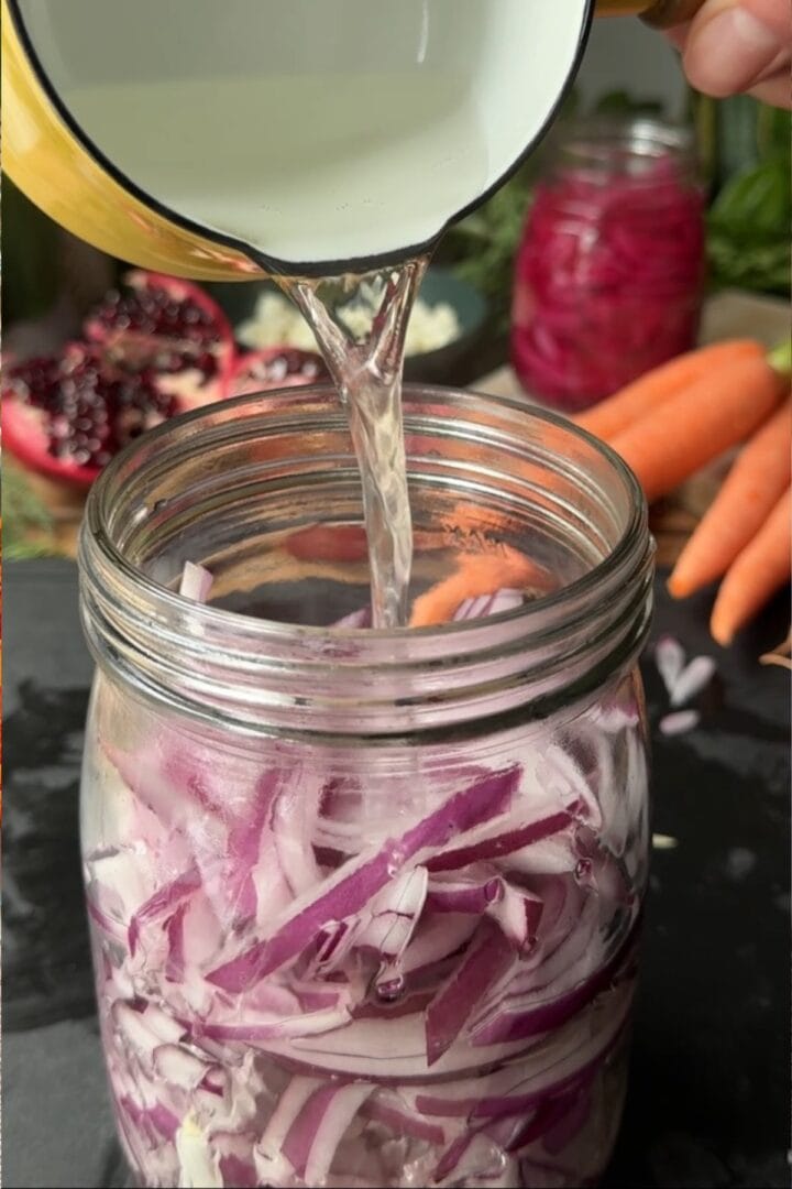 Pouring pickling brine onto red onions.