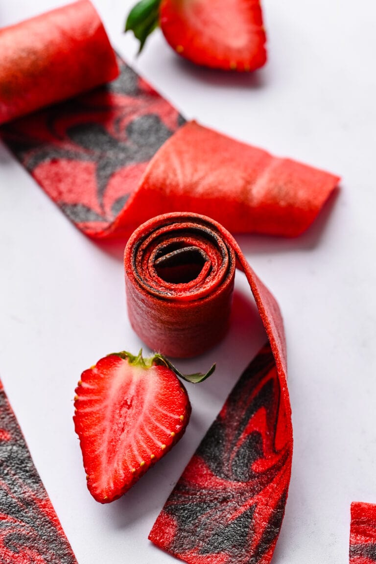 Strawberry-themed fruit leather and fresh strawberries on white background.