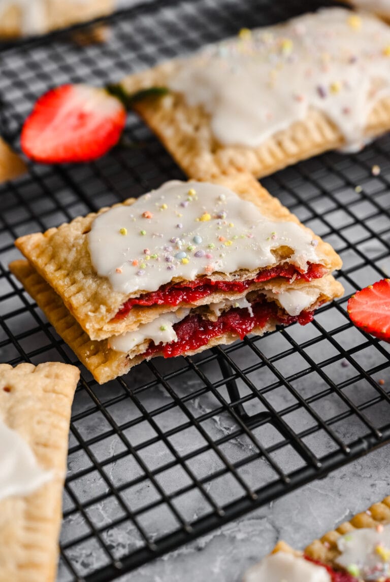 Fried strawberry shortcake dessert bar topped with white icing and colorful sprinkles on a cooling rack.