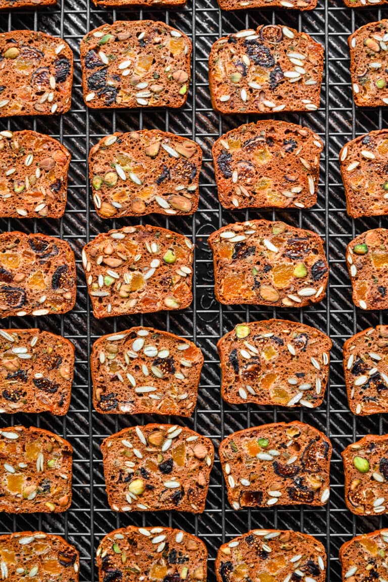 Almond fruitcake slices with dried fruits on cooling rack.