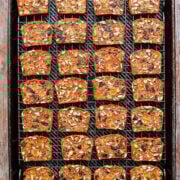 Bright fruitcake slices topped with seeds on a baking sheet.