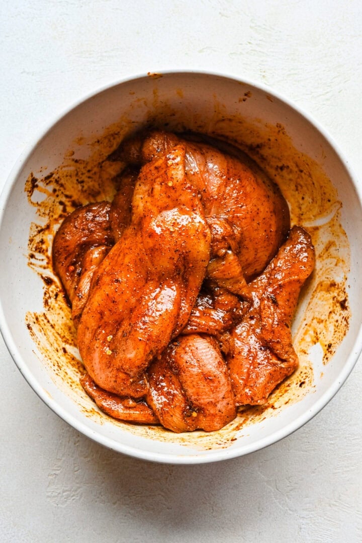 Overhead view of chicken in a bowl in marinade.