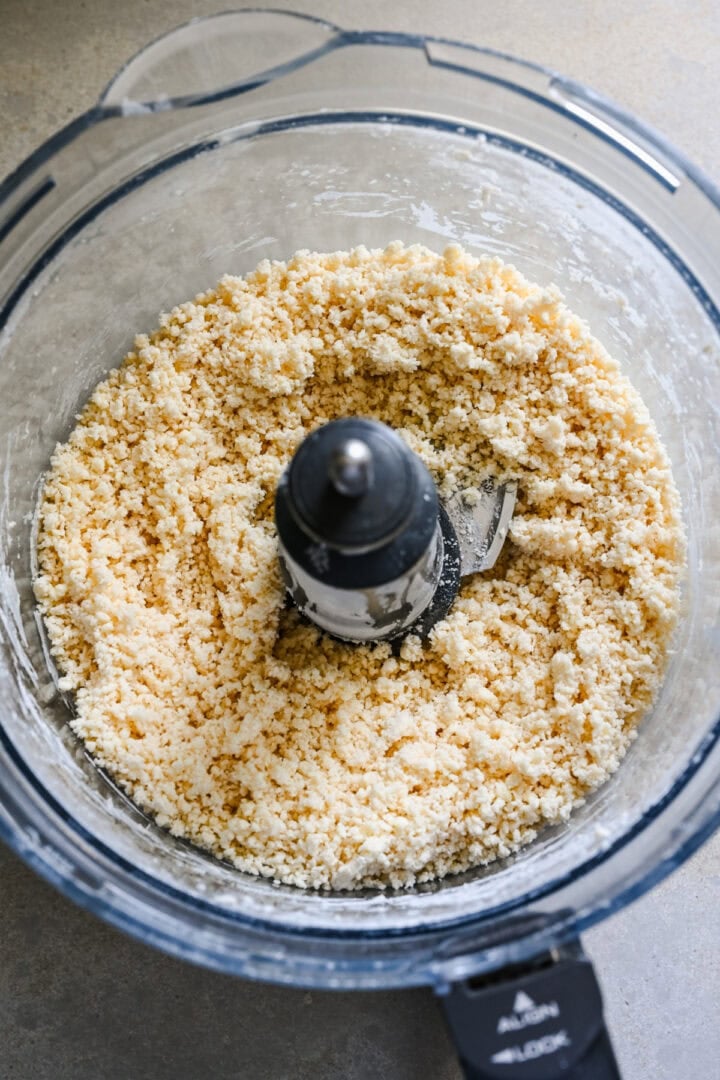 Overhead view of butter and dry ingredients in a food processor after processing.