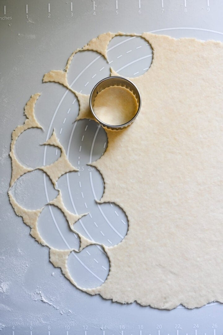 Cutting dough into rounds with a fluted pastry ring.