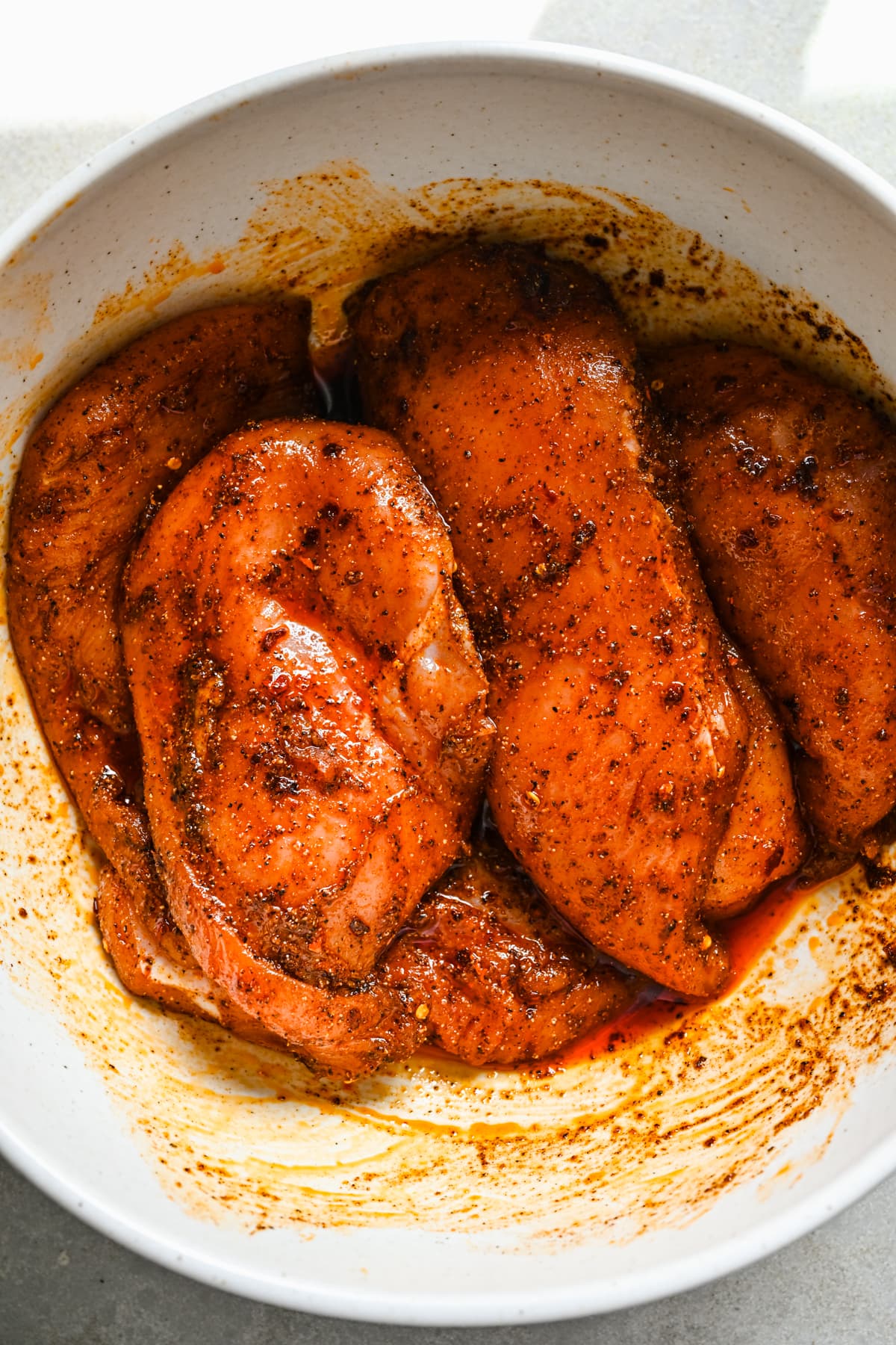 Chicken in a bowl being marinated.