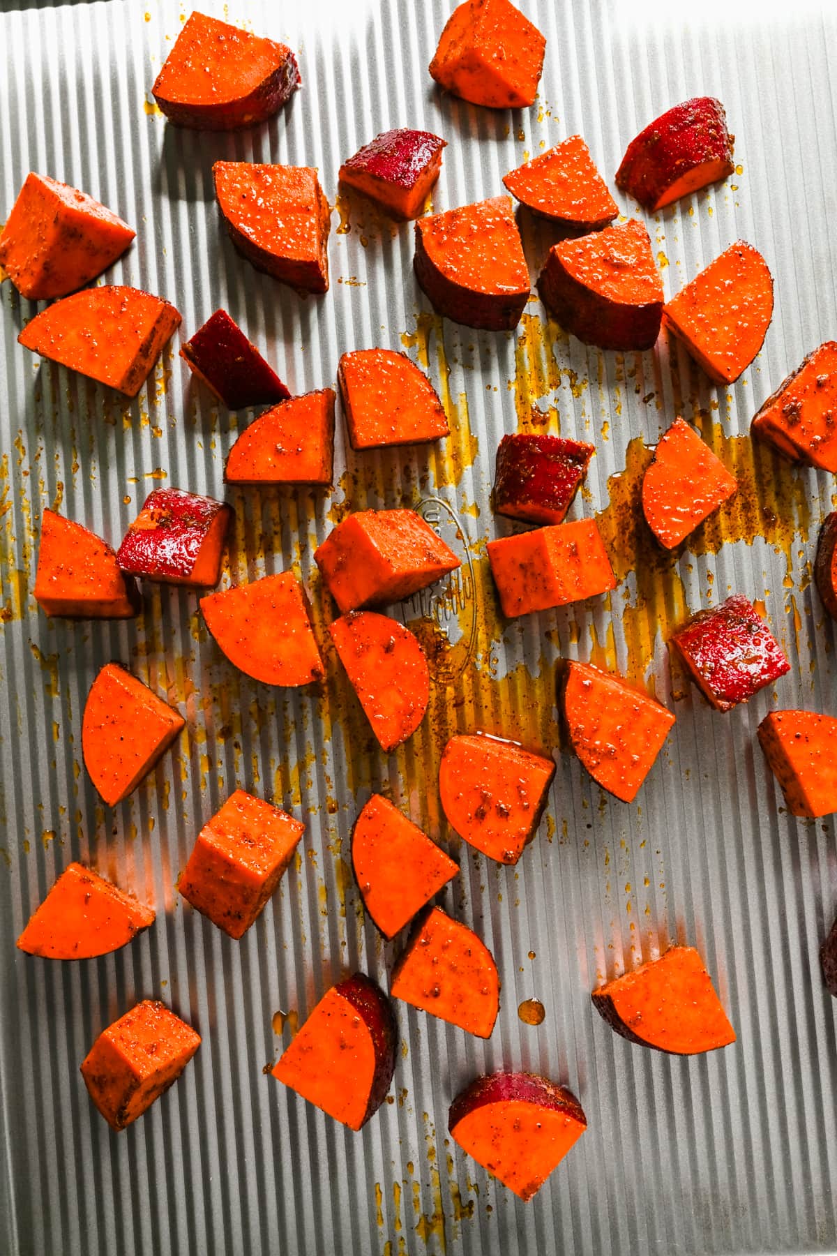 Raw sweet potatoes on a sheet pan.