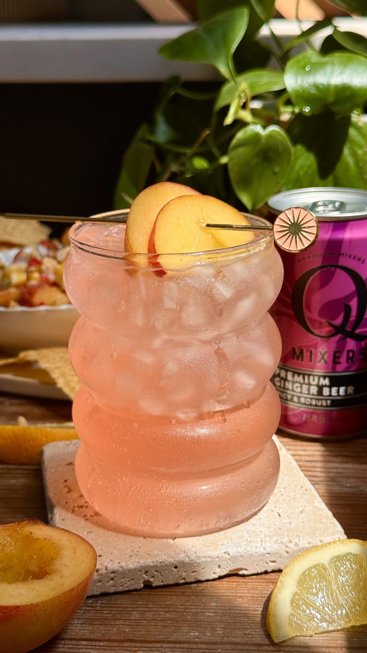 Side view of peach ginger cocktail with peach slices for garnish.