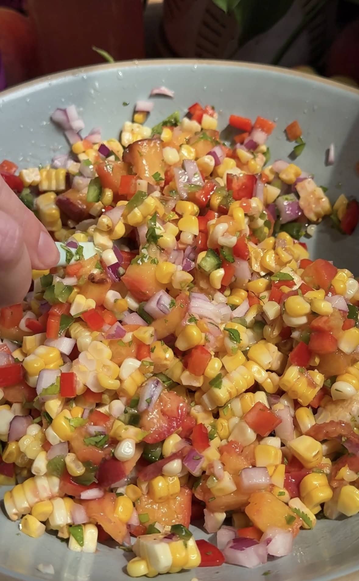 Side view of peach corn salsa in a bowl.