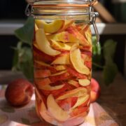 Side view of peaches in a jar with vodka.