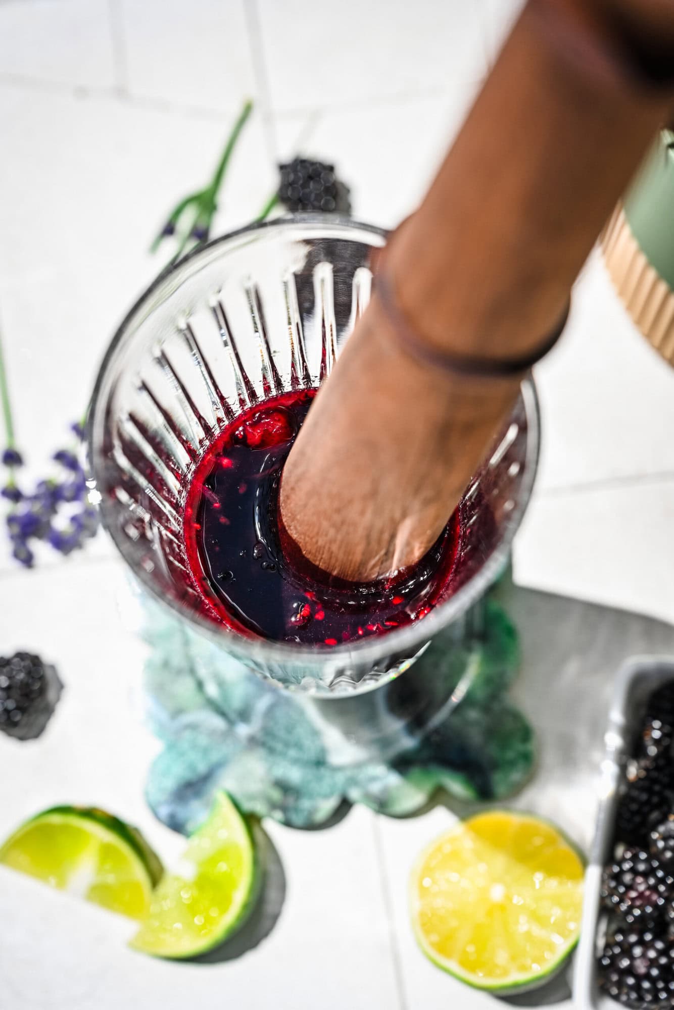 Smashed blackberry, lime and mint in a highball glass with a muddler.