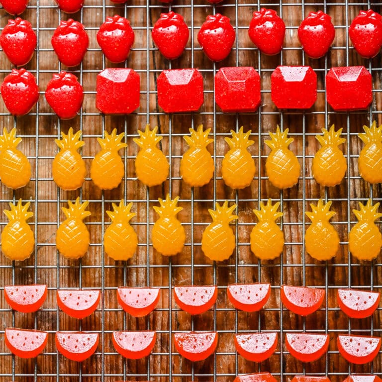 Pink and yellow fruit-shaped candies on a wire cooling rack, ready to serve or decorate desserts.