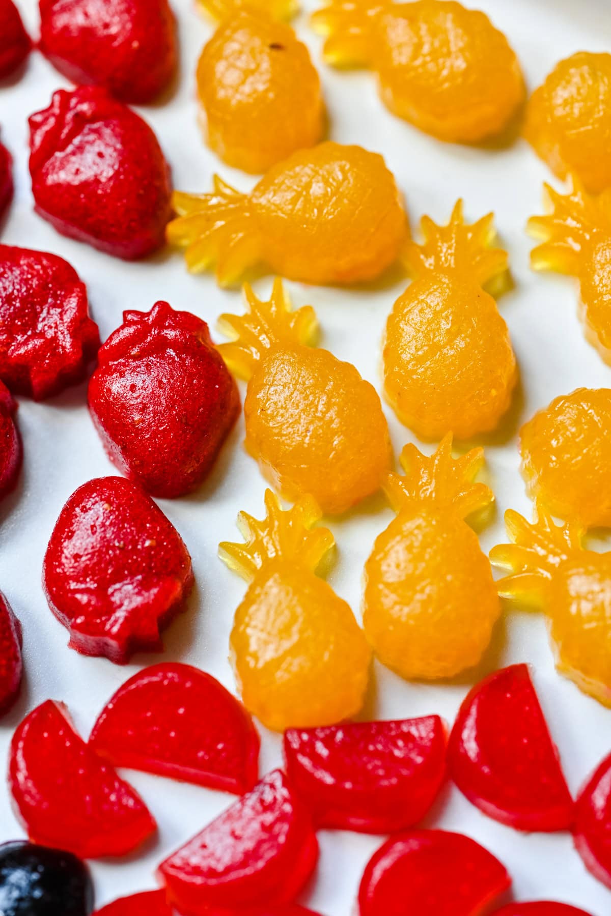 Pineapple and strawberry fruit snacks on a plate.