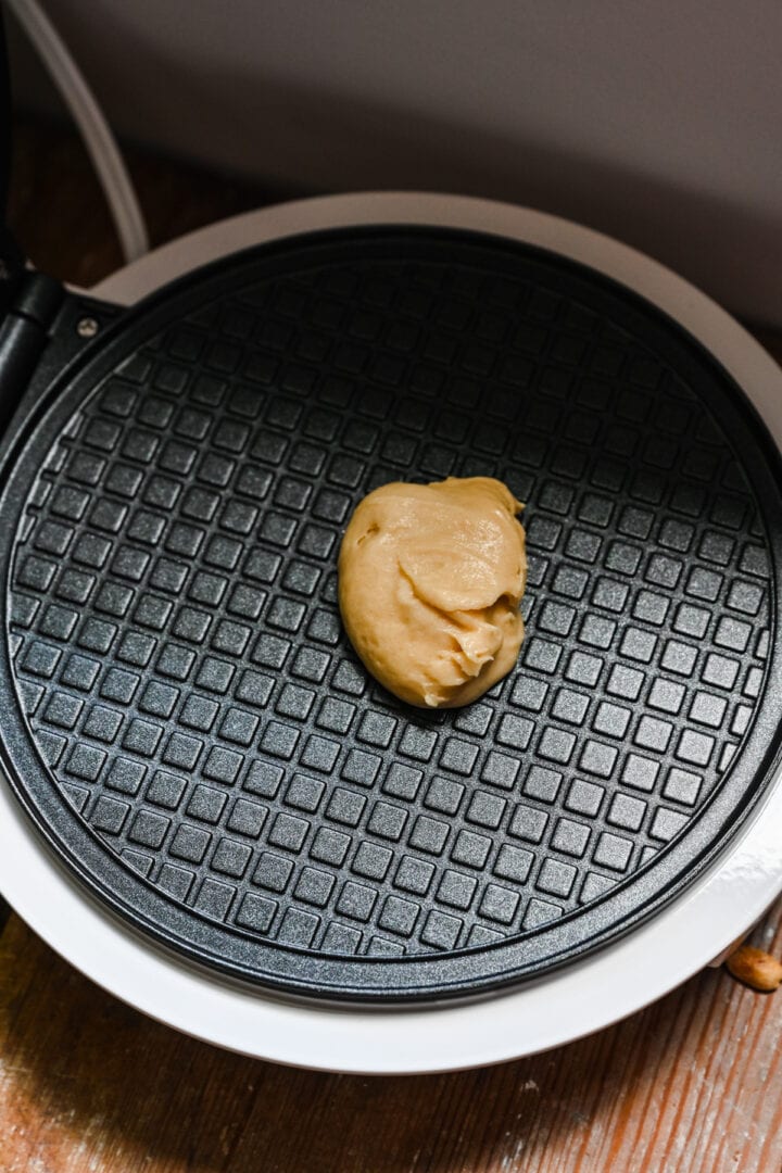 Dollop of waffle cone batter in a waffle maker.