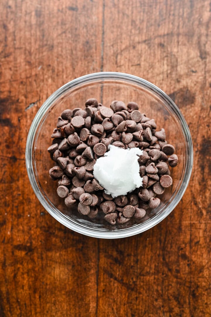 Overhead view of chocolate chips and coconut oil in a bowl.