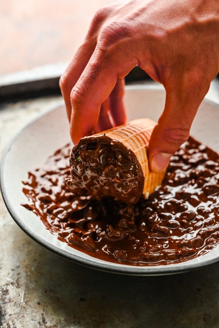 Dipping ice cream taco in chocolate and peanuts.