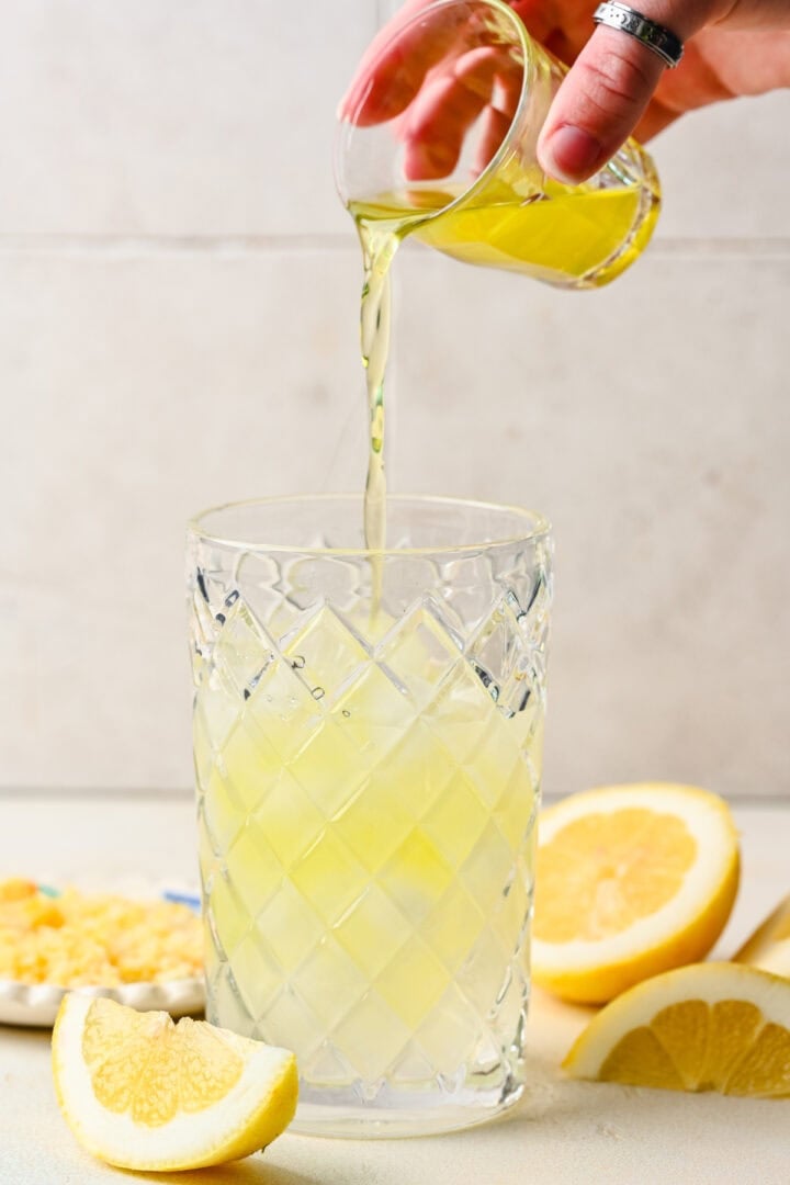 Pouring limoncello into a cocktail shaker.