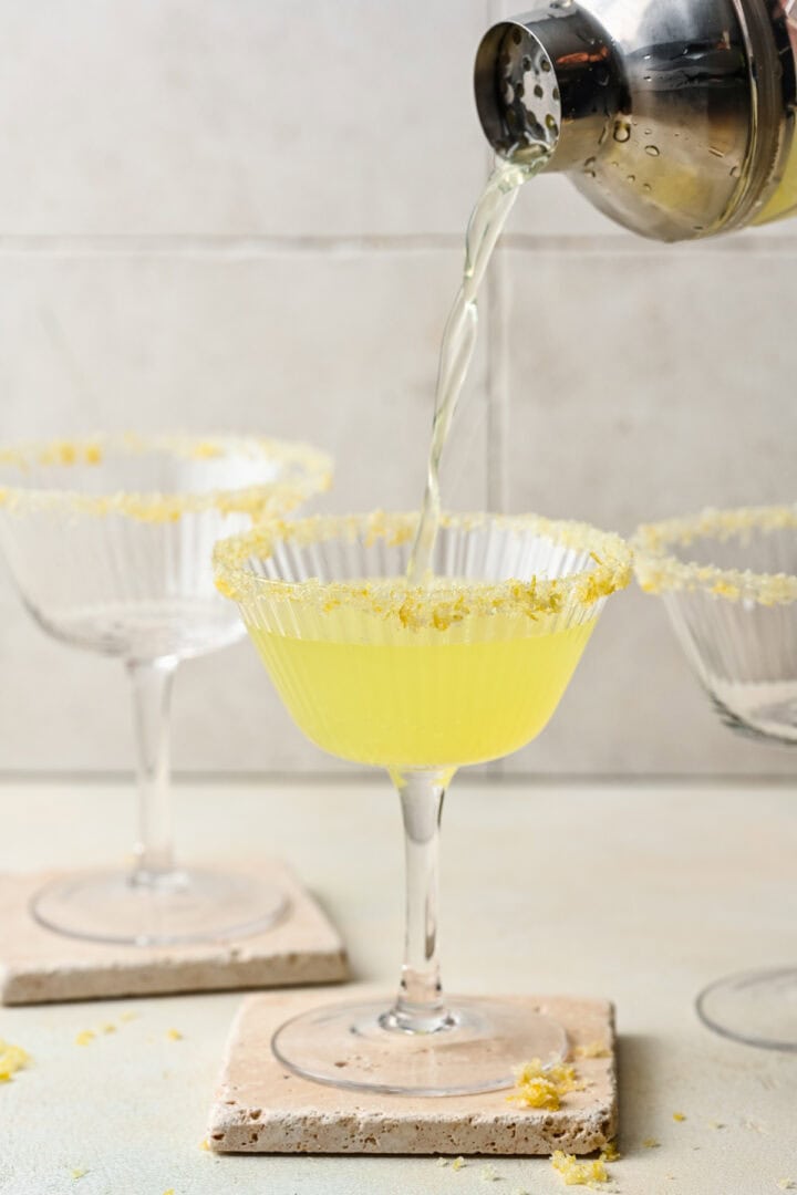 Pouring limoncello martini into a glass.