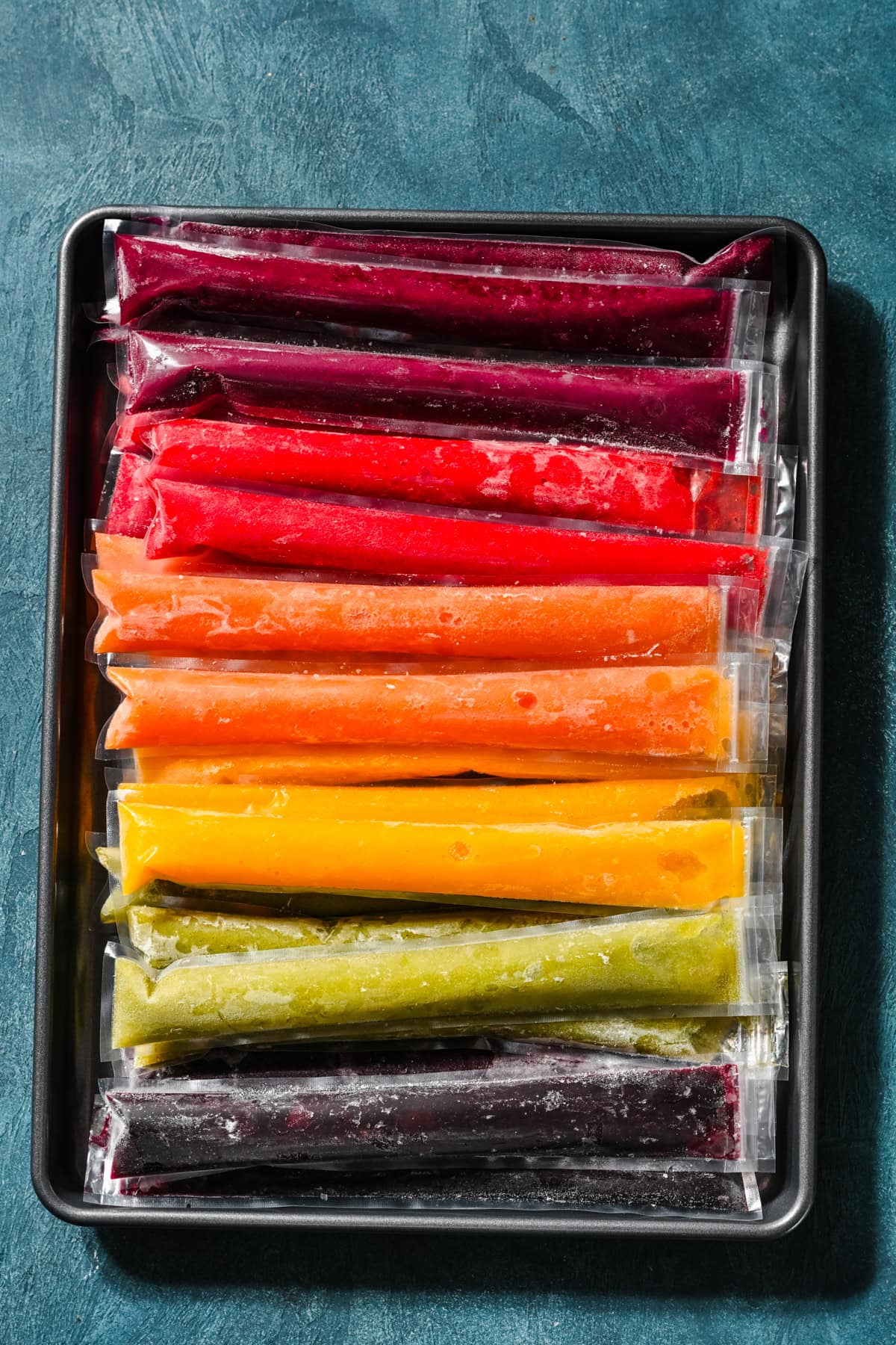 Overhead view of frozen popsicles on a sheet pan.