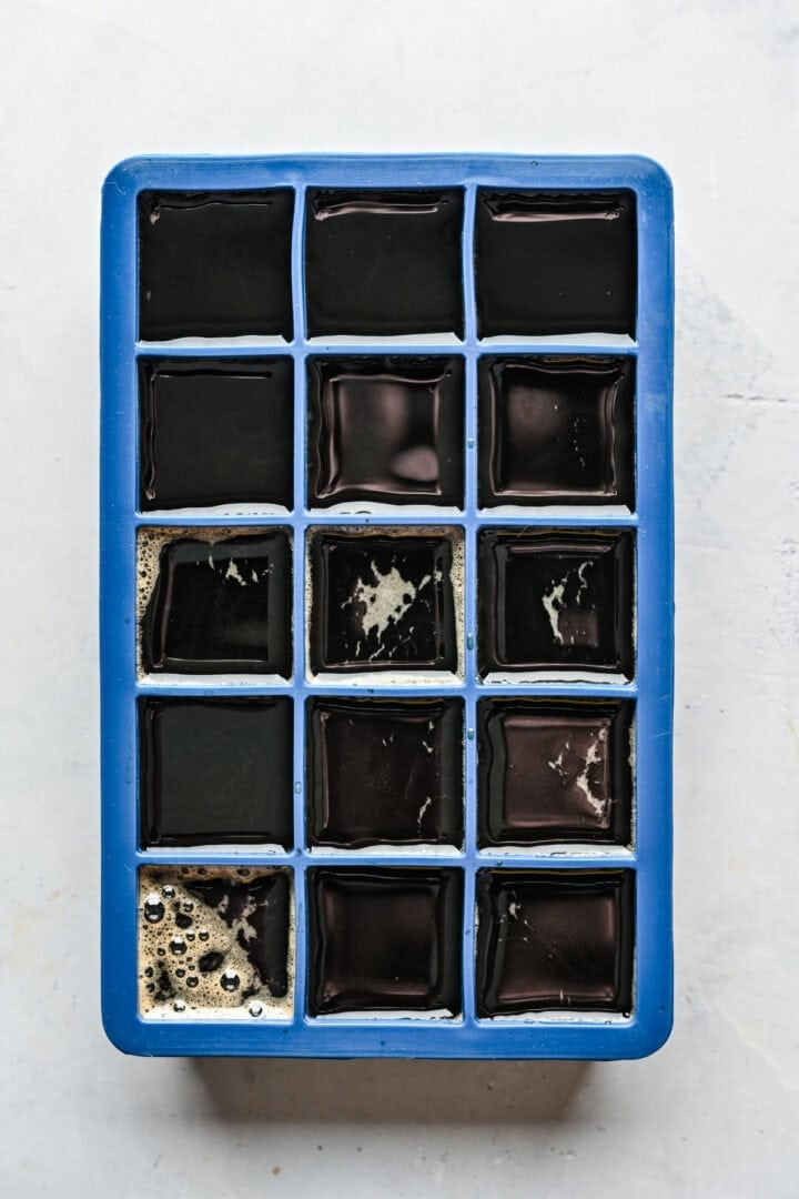 Overhead view of unfrozen espresso cubes in an ice cube tray.