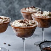 Frosted chocolate desserts topped with whipped cream and coffee beans in martini glasses.