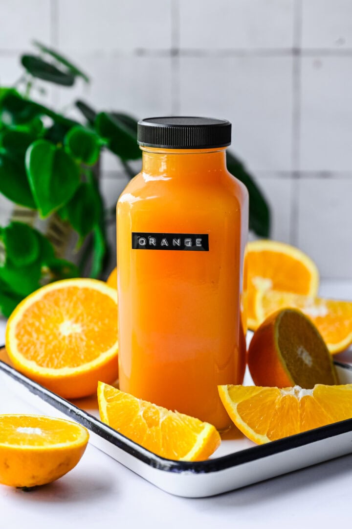 Front view of orange gatorade in a glass bottle.