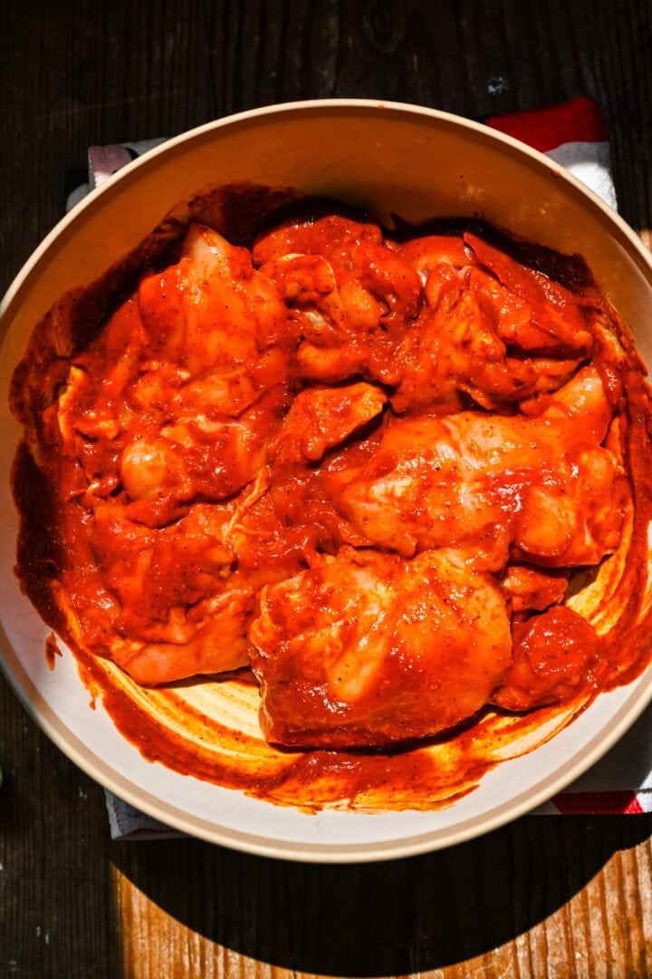 Chicken thighs marinating in a bowl.