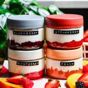 Front view of blackberry, raspberry, strawberry, and peach yogurt in jars.