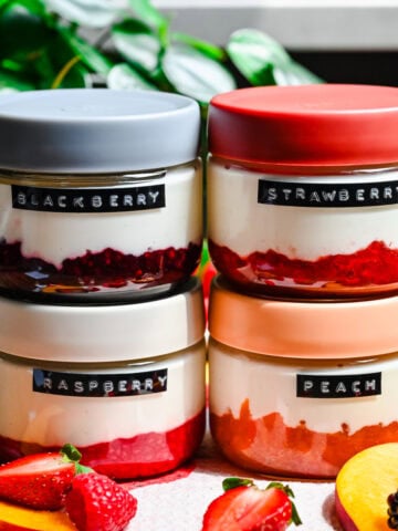 Front view of blackberry, raspberry, strawberry, and peach yogurt in jars.