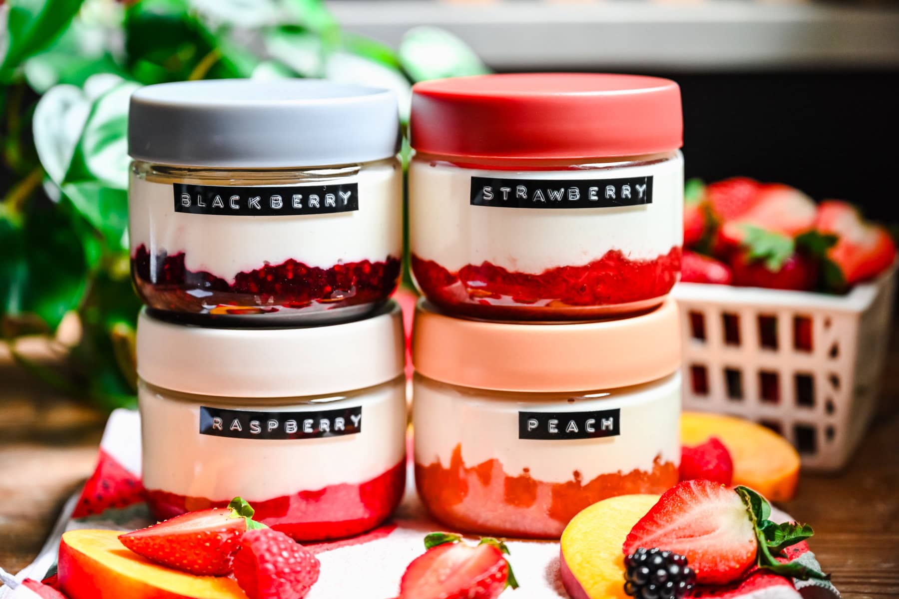 Front view of blackberry, raspberry, strawberry, and peach yogurt in jars.