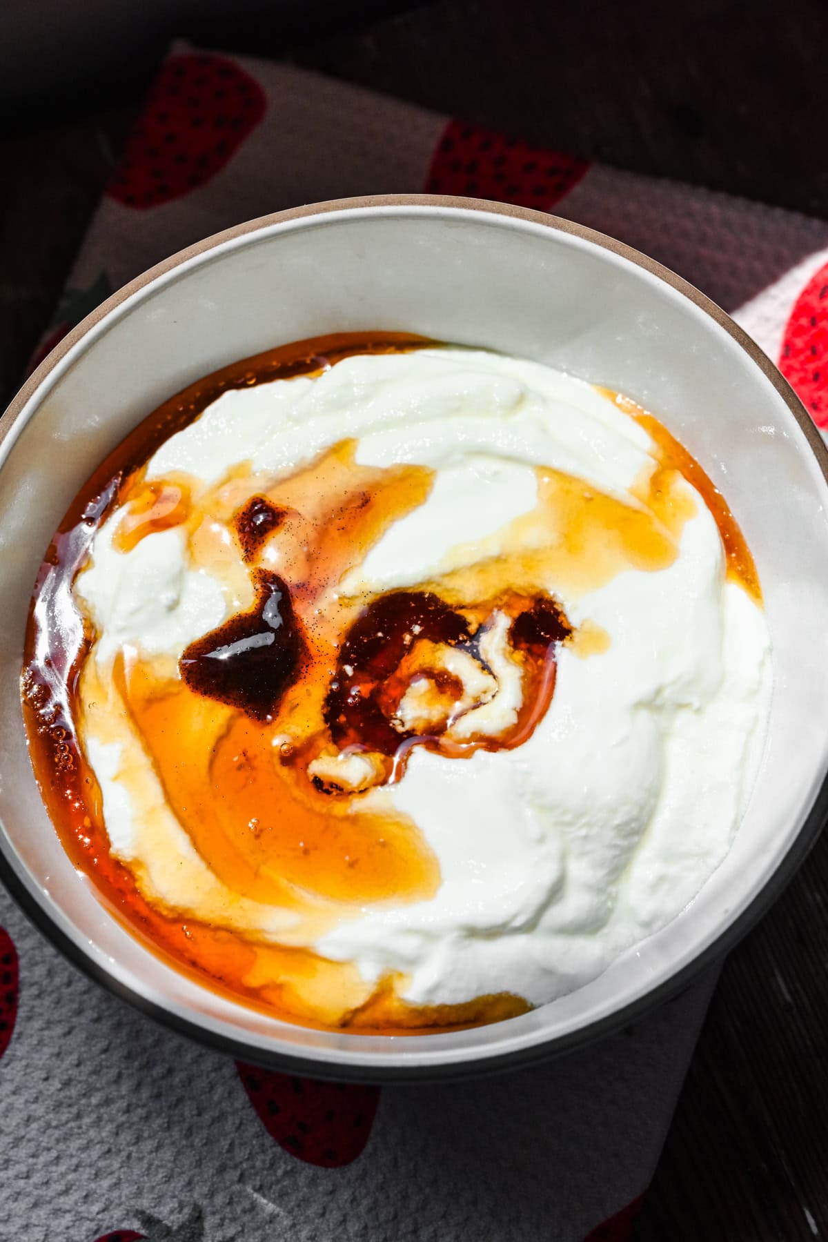 Yogurt being mixed with maple syrup and vanilla bean paste.