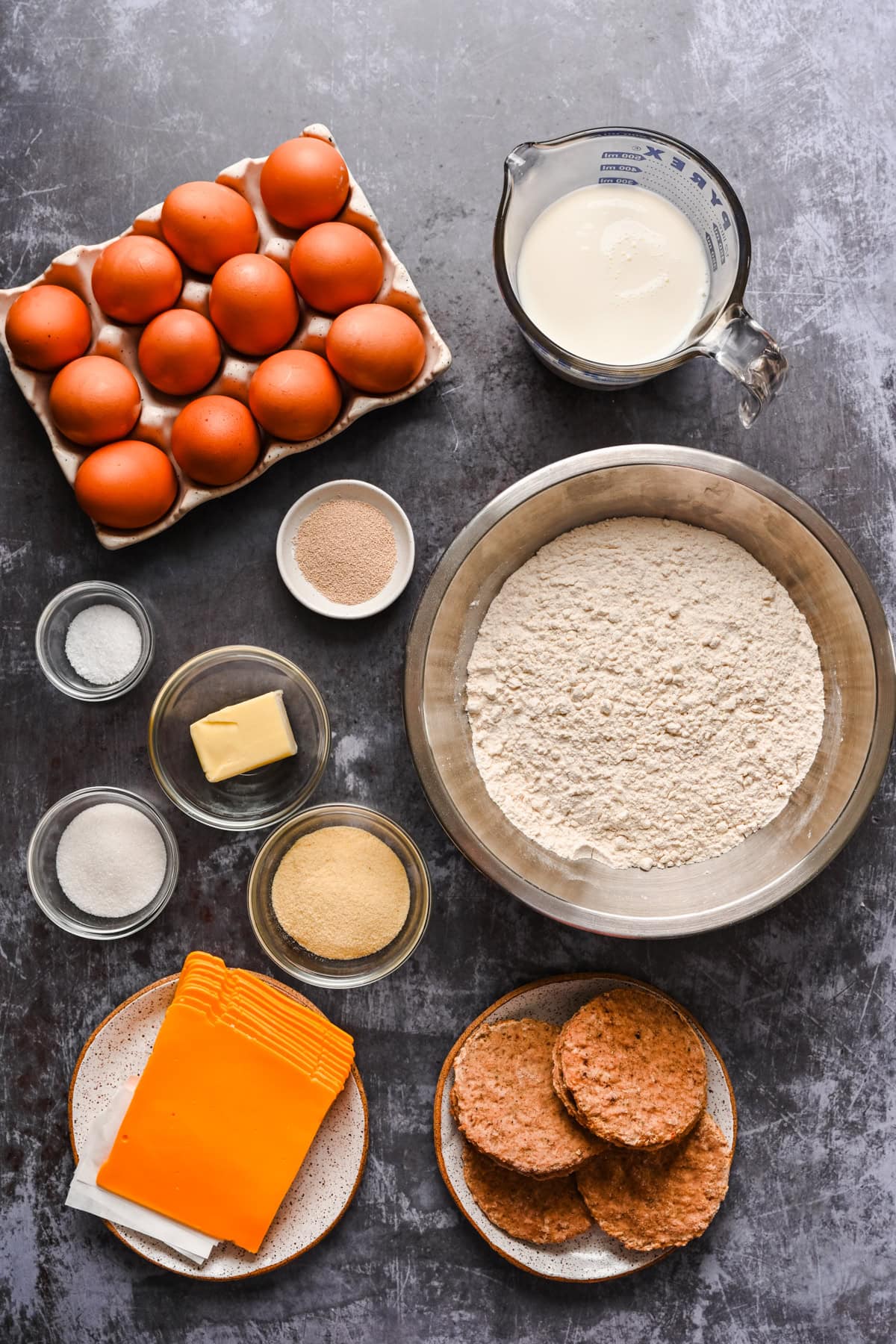 Overhead view of egg mcmuffin ingredients, including eggs, flour, cheese.