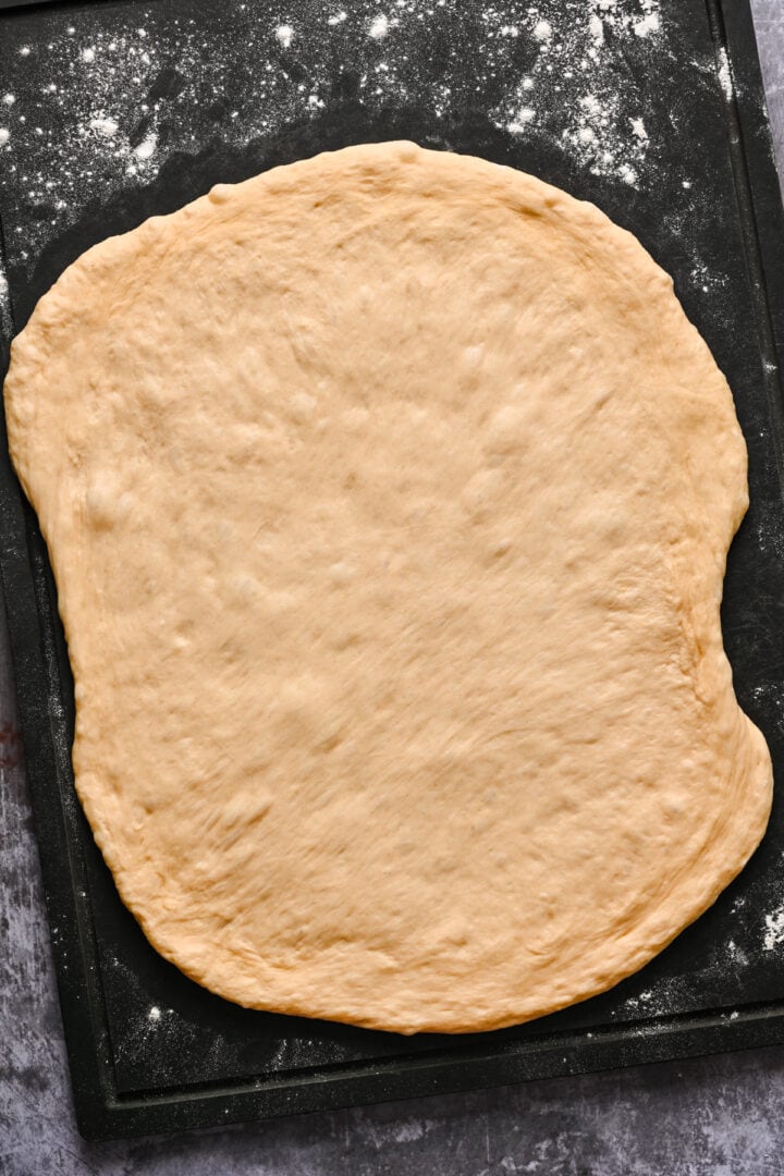 Dough patted down on top of a cutting board.