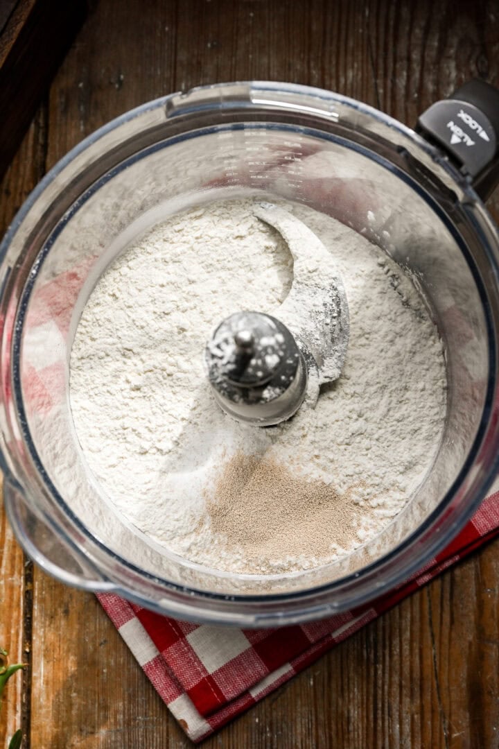 Overhead view of dry ingredients for dough in a food processor.