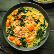 Soup in a bowl with noodles, butternut squash, and kale.