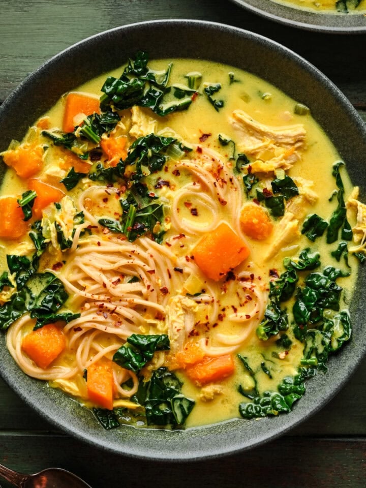 Soup in a bowl with noodles, butternut squash, and kale.