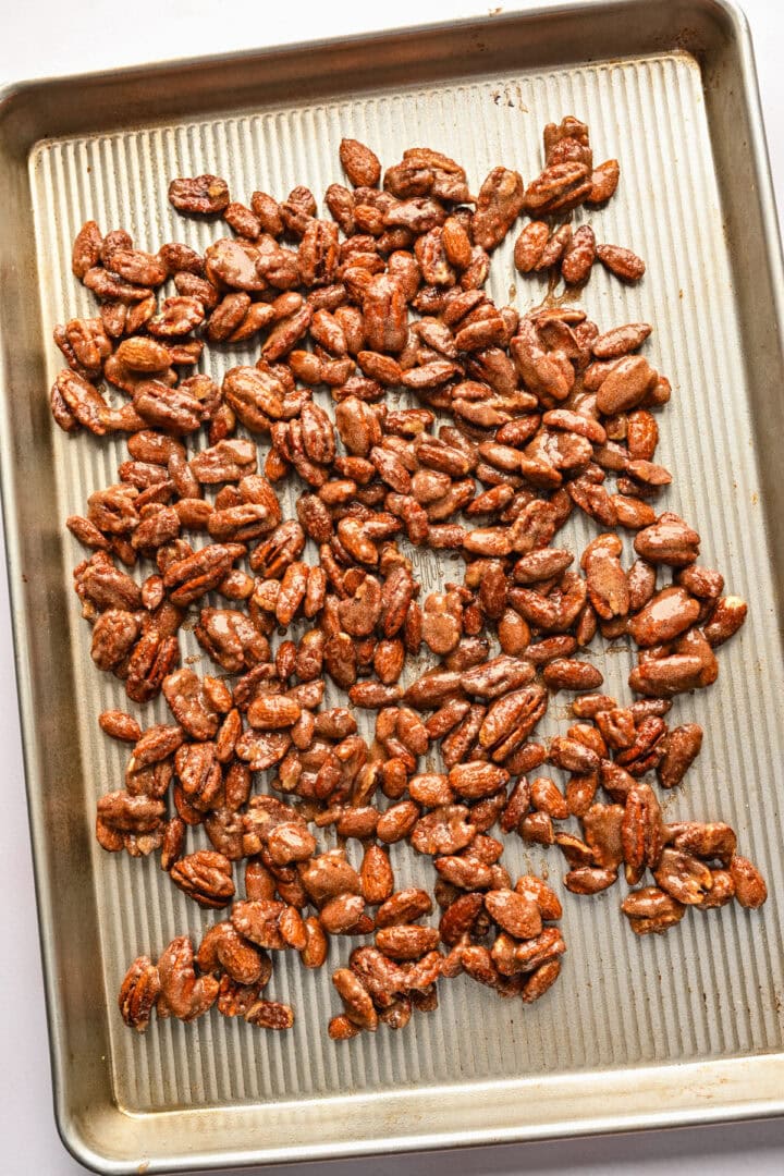 Overhead view of candied nuts on a sheet pan.