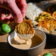 Brussel sprout being dipped in sauce.