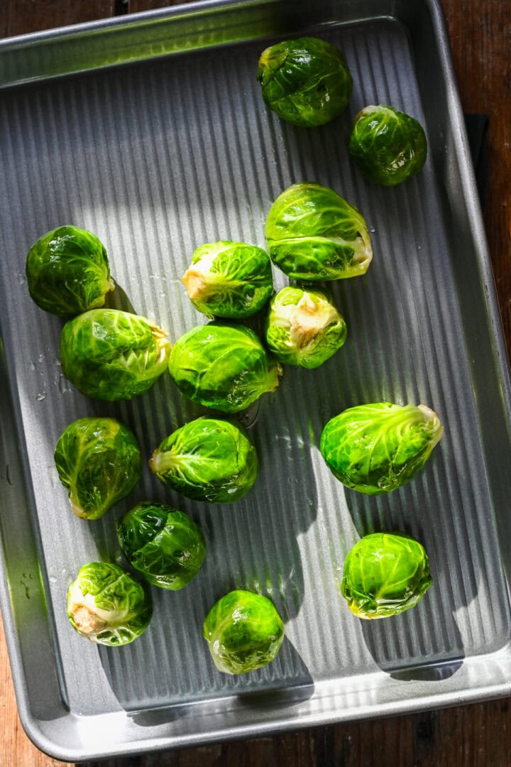 Overhead view of brussels sprouts on a sheet pan before cooking.