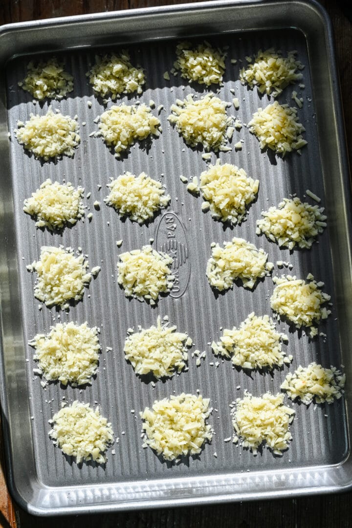 Several dots of cheese placed on a sheet pan.