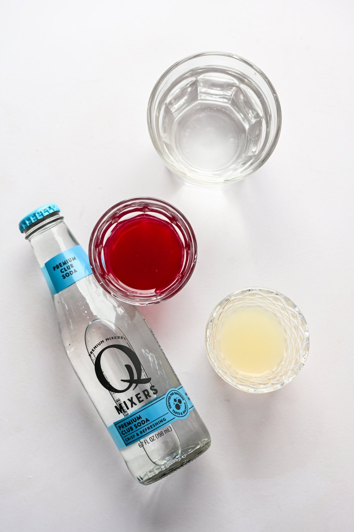 Overhead view of sugar plum cocktail ingredients, including club soda and grenadine.