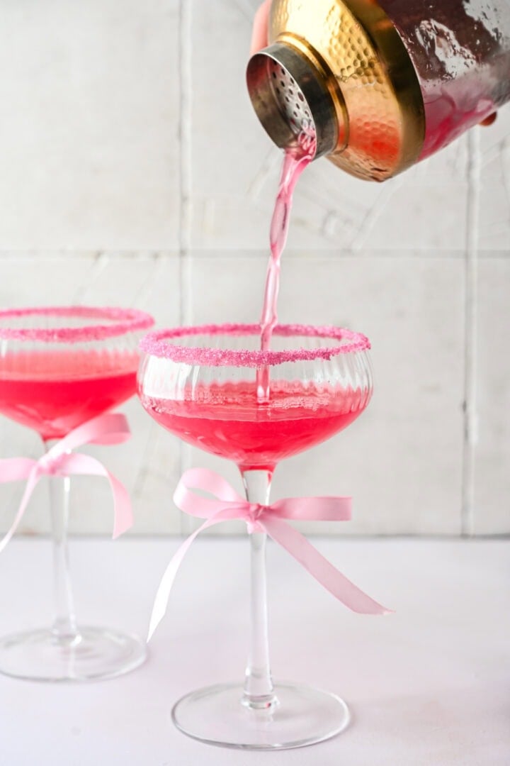 Pouring cocktail into a coupe glass.
