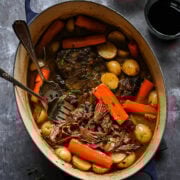 Overhead view of pot roast in a pot with carrots and potatoes.