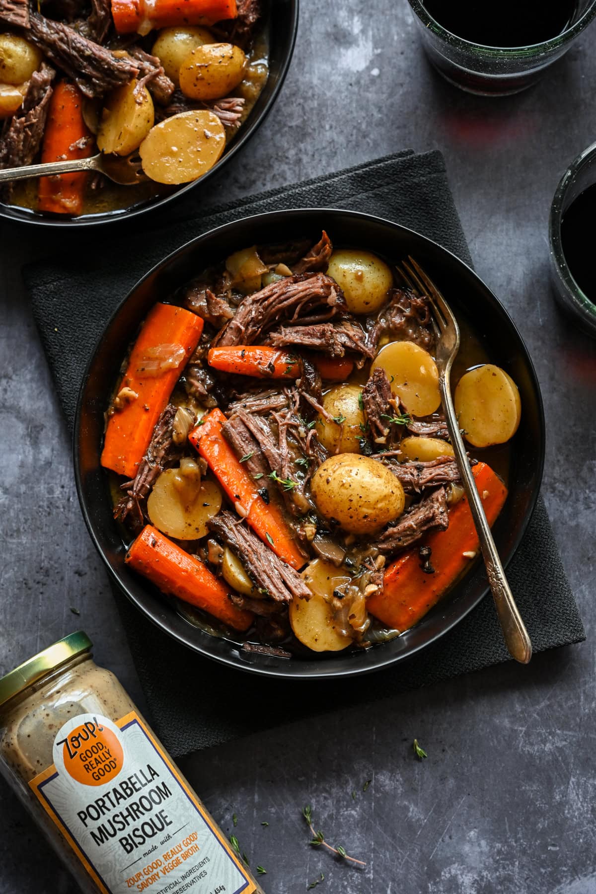 Overhead view of pot roast in a bowl next to a jar of mushroom soup.