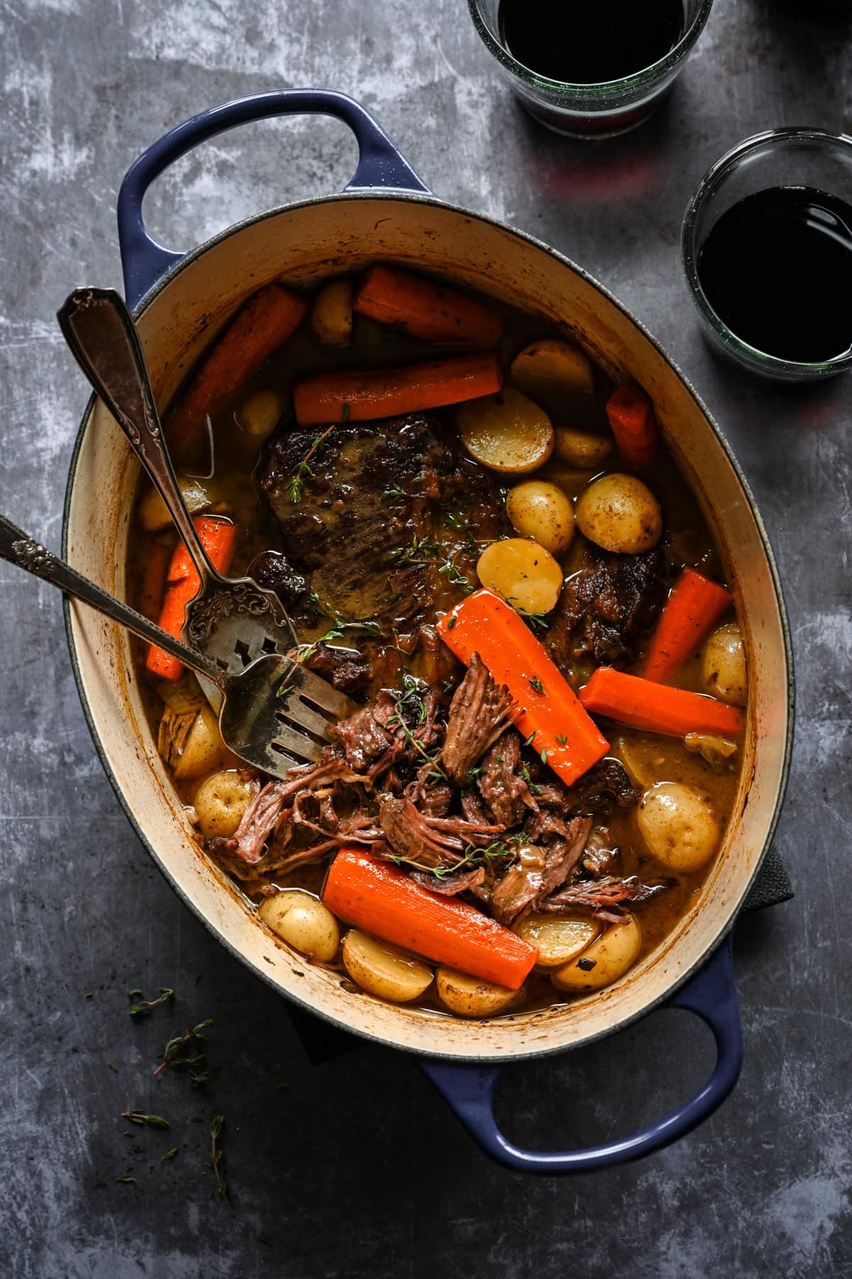 Overhead view of pot roast in a pot with carrots and potatoes.