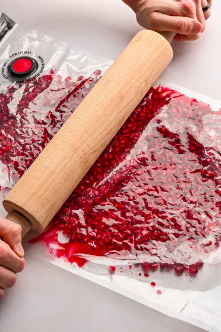 Crushing pomegranate arils with a rolling pin.