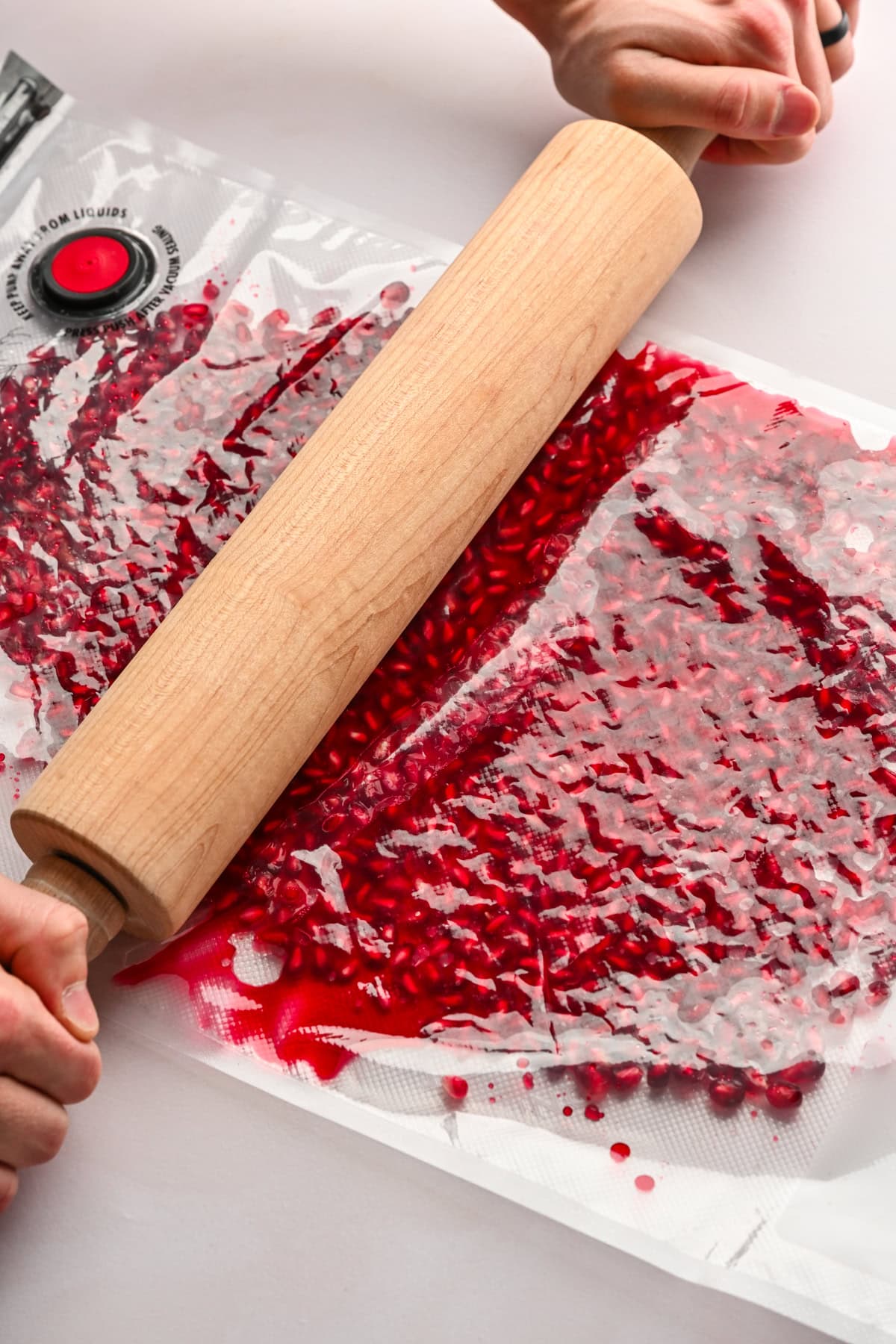 Crushing pomegranate arils with a rolling pin.