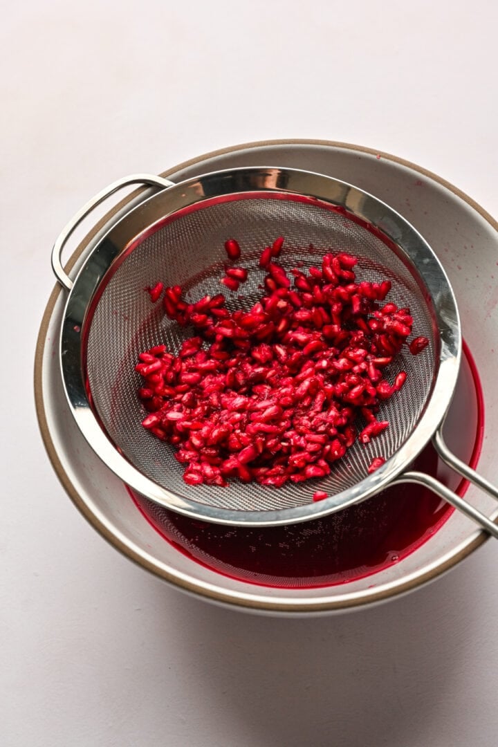 Pomegranate seeds in a strainer after squeezing the juice out of them.
