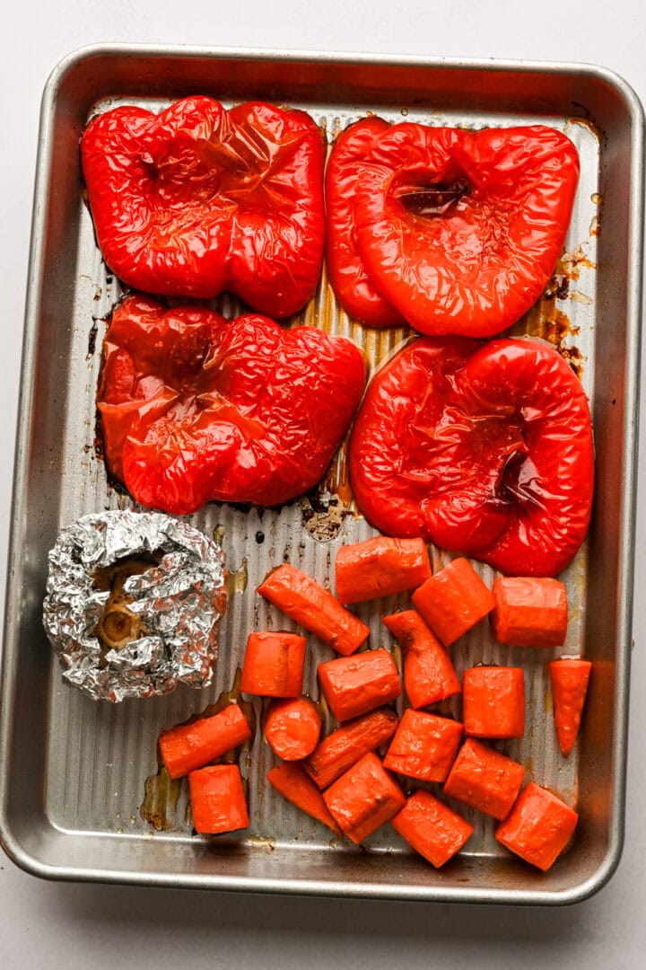Red peppers, carrots and garlic on a sheet pan after roasting. 