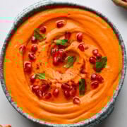 Creamy carrot soup garnished with pomegranate seeds and fresh mint. Perfect healthy meal for brunch or dinner.